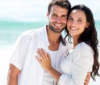 A portrait photo of a man and woman wearing white tops in a beach